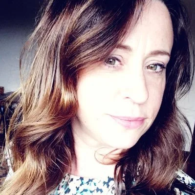 A woman with long dark hair, looking into the camera.