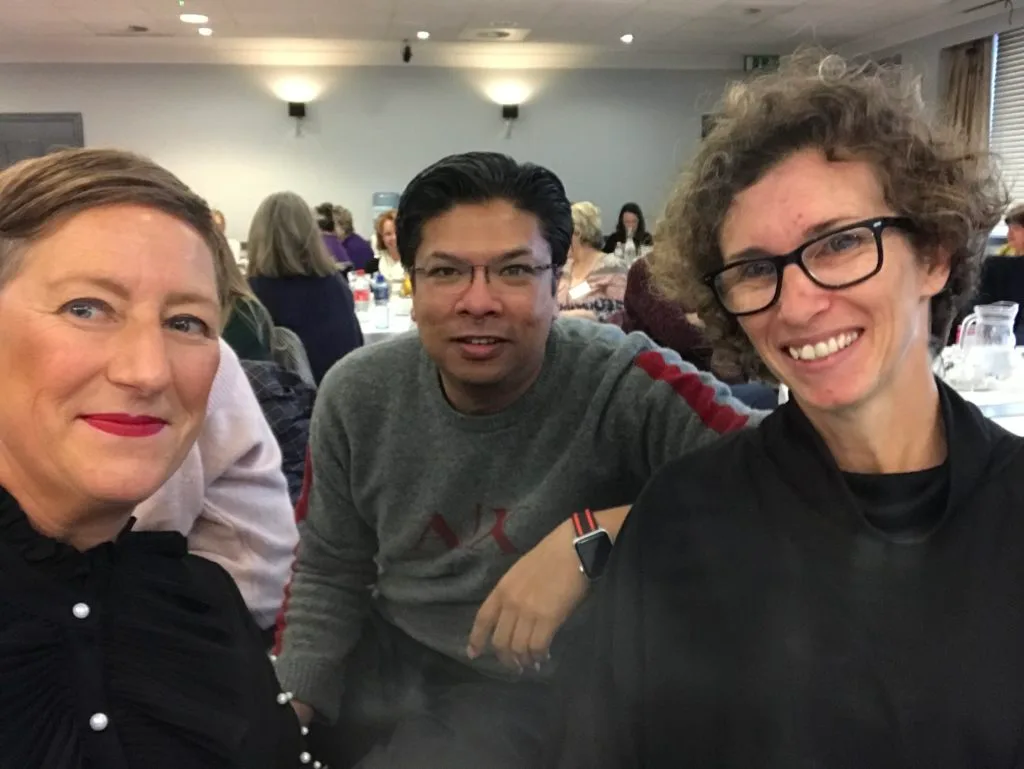 Three delegates together at the conference table, smiling for the camera.