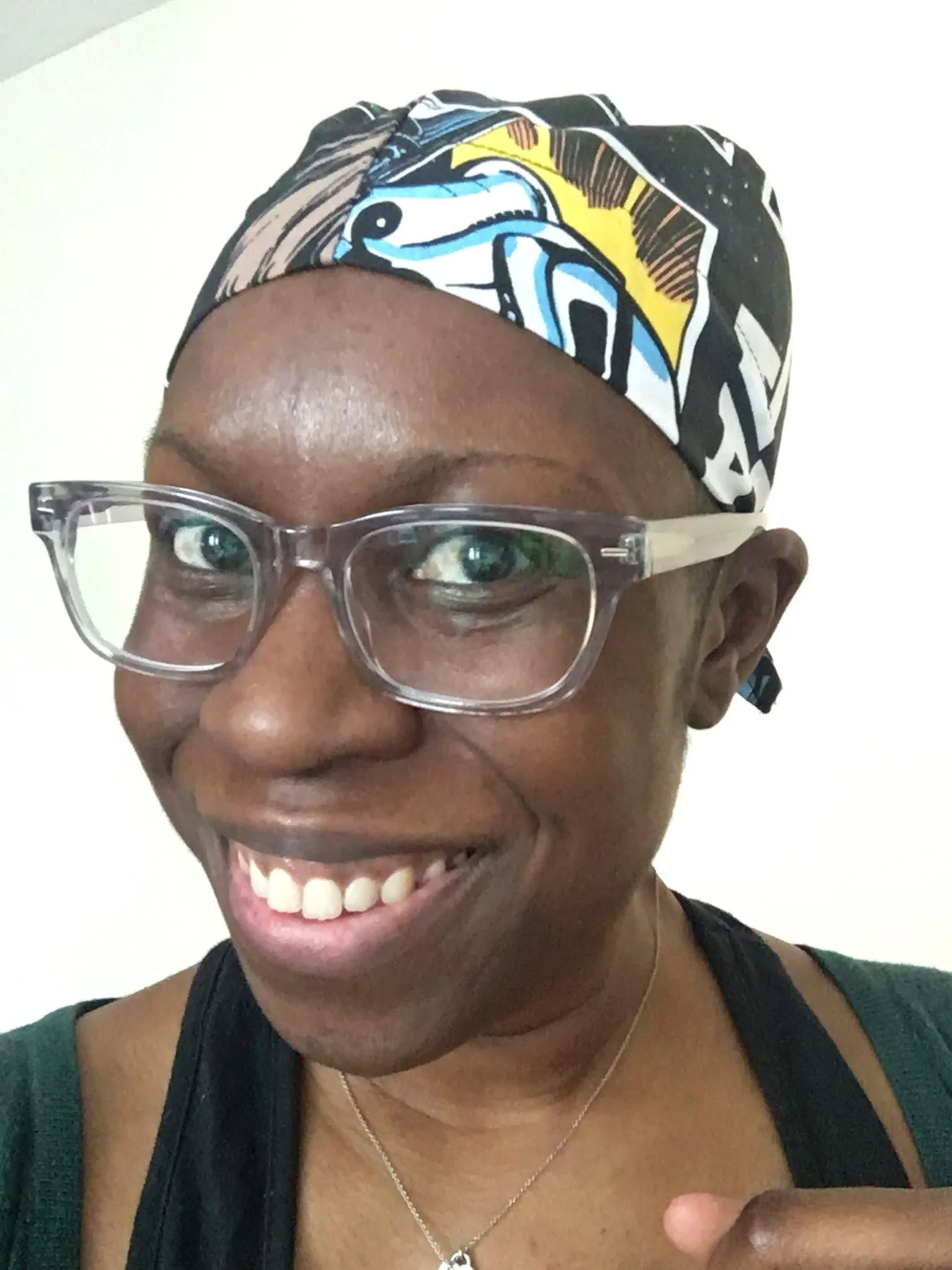 Miranda Ashitey smiling into the camera, wearing a brightly patterned headscarf.