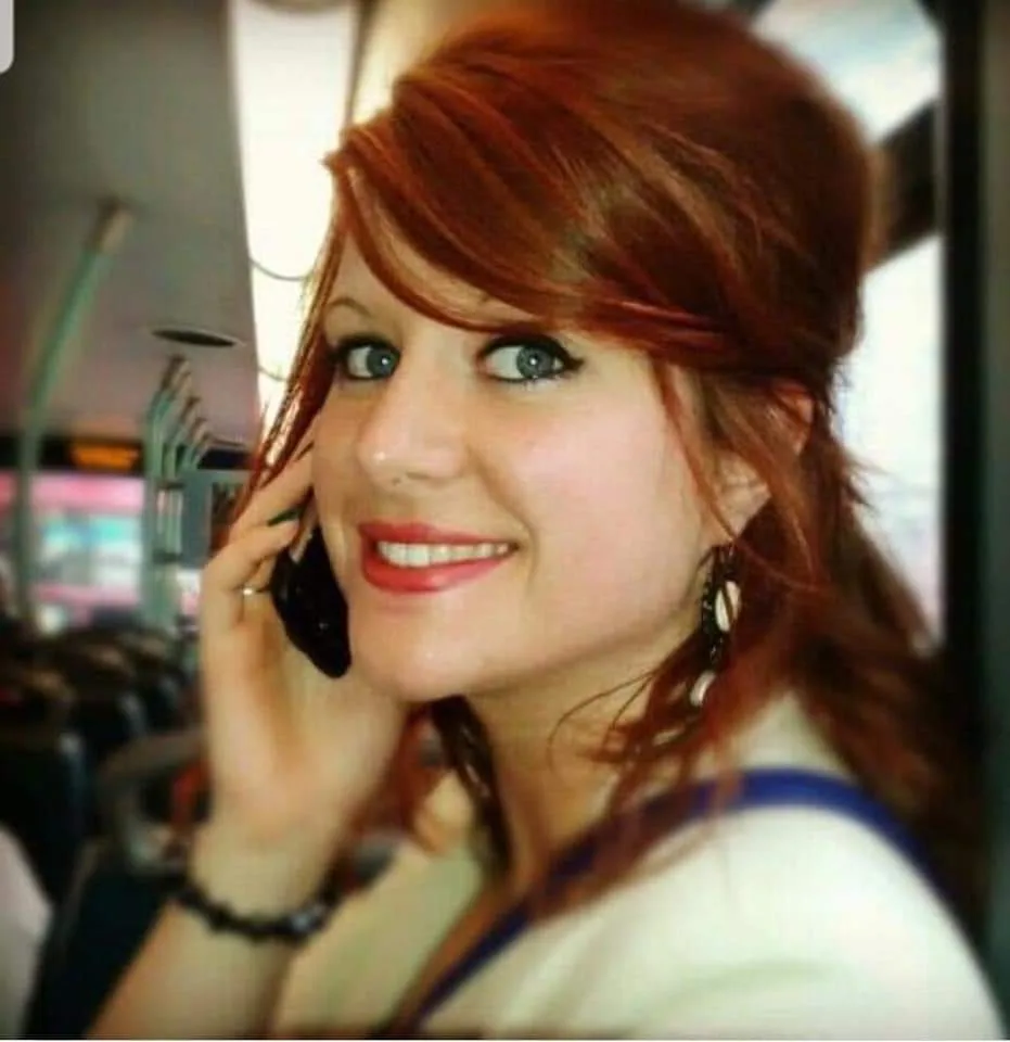 Connie, with red hair, on the phone and smiling over her shoulder.