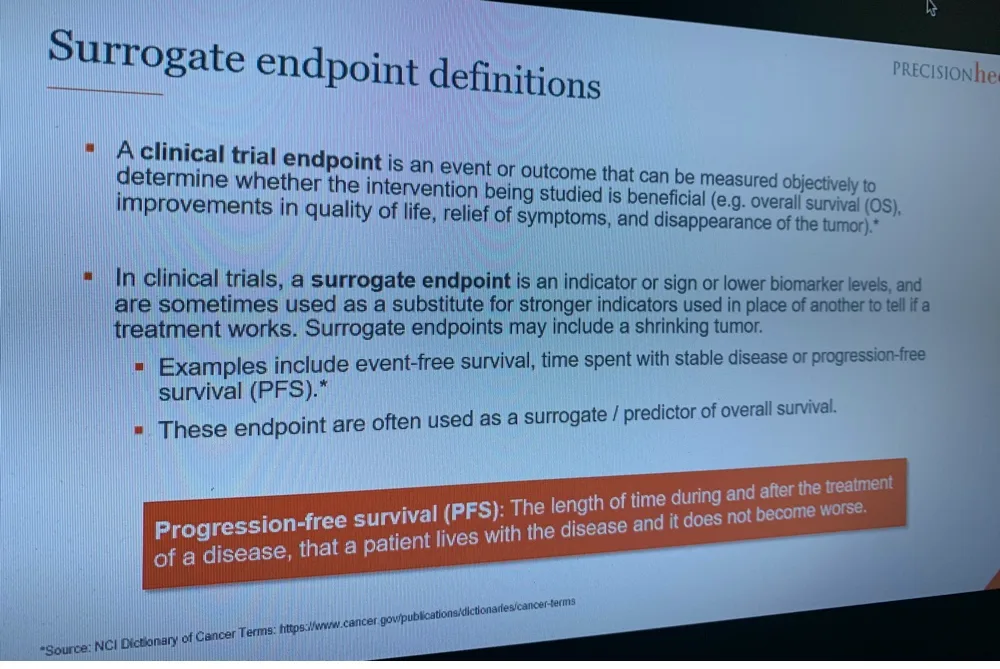 A roundtable slide defining surrogate endpoints, and defining progression-free survival as the length of time during and after treatment that a patient lives with the disease without it getting worse.