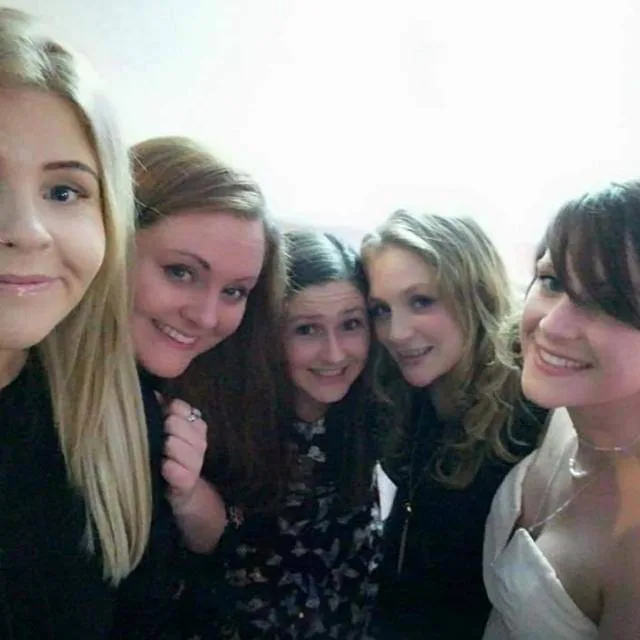 Five friends together on a night out, arms round each other.