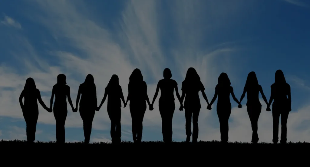 A line of women in silhouette, holding hands against an evening sky.