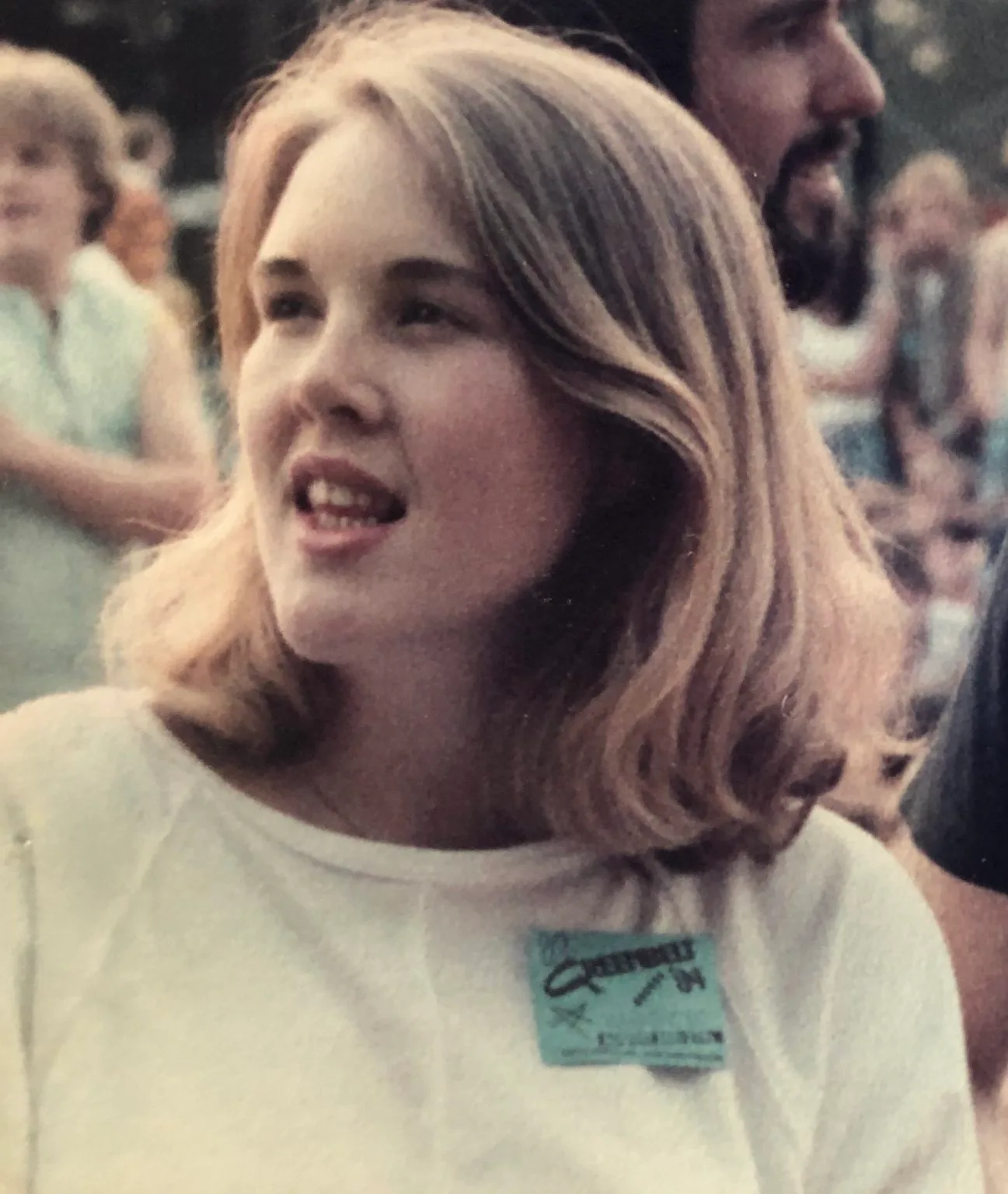 An old photograph of a young woman at an event, wearing a name badge.